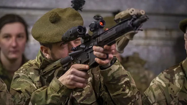 A man in uniform looks through the sight of his weapon.