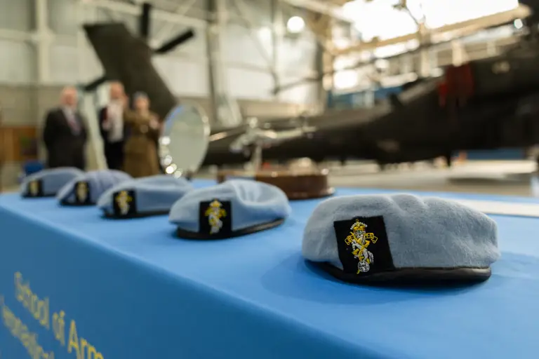 A row of light blue berets sit on a table with a blue tablecloth.
