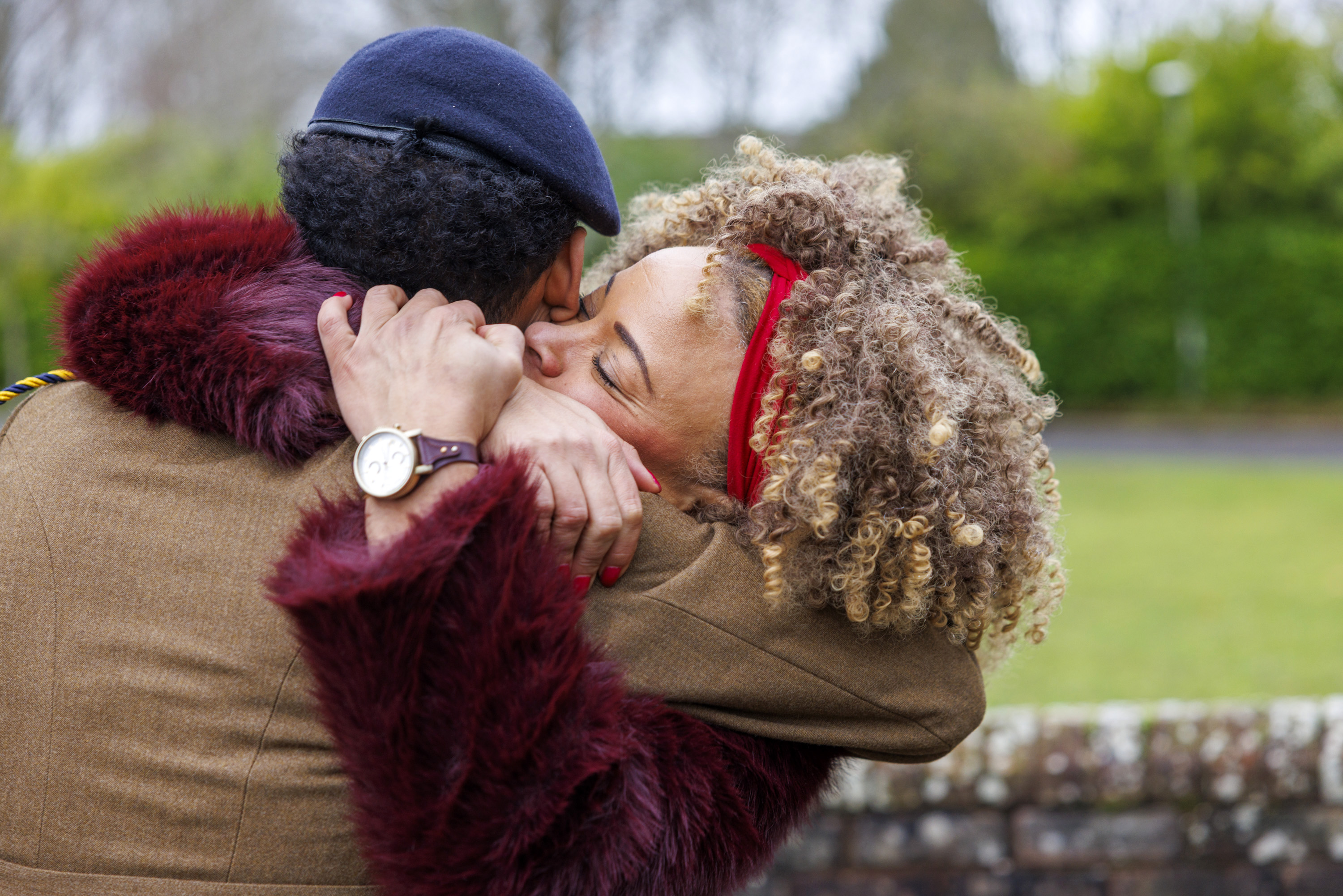 A mother and son embrace warmly outdoors.