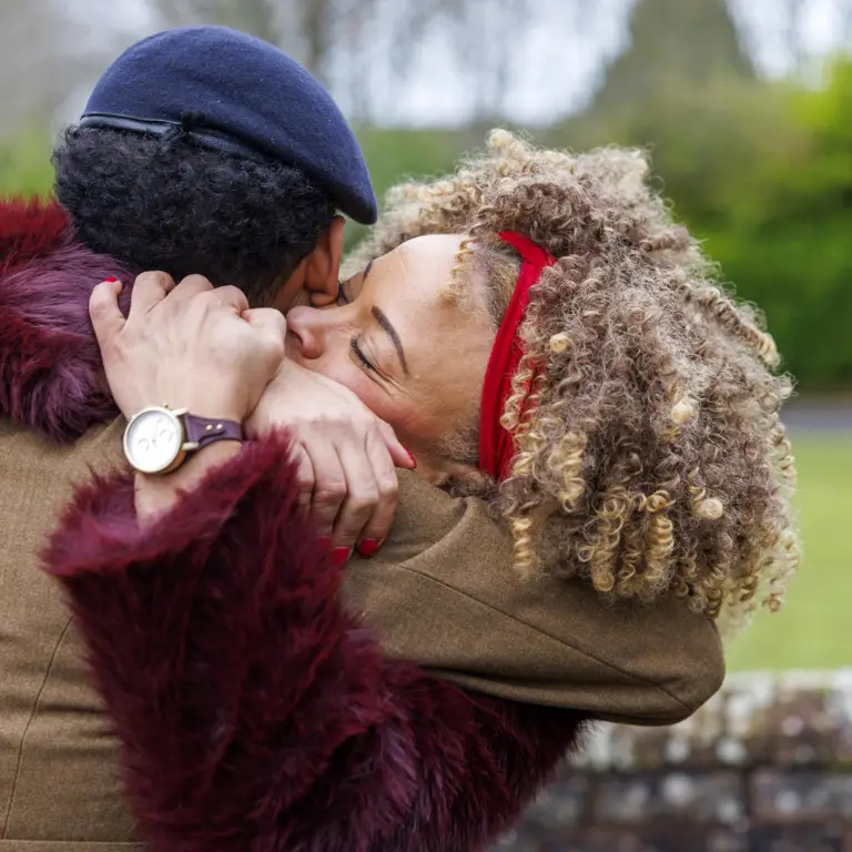 A mother and son embrace warmly outdoors.