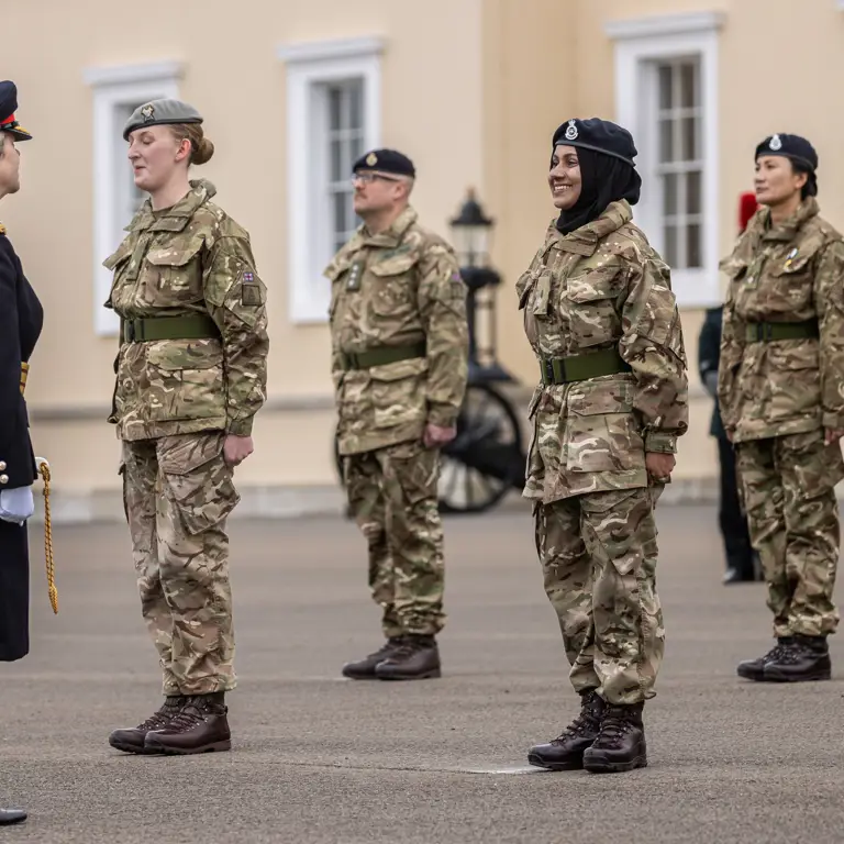 A female officer in a dark uniform inspects a line of six soldiers standing at attention in camouflage gear.