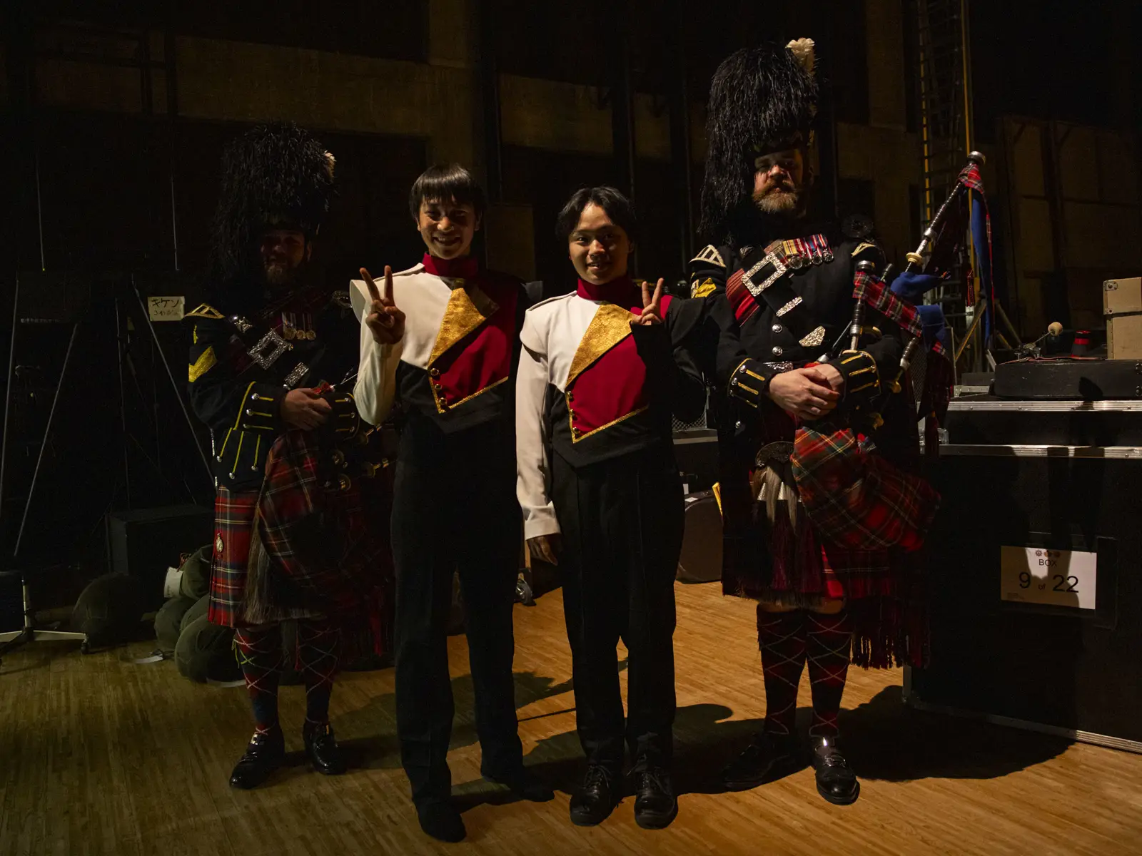 Two bagpipers in kilts are pictured with two Japanese musicians.