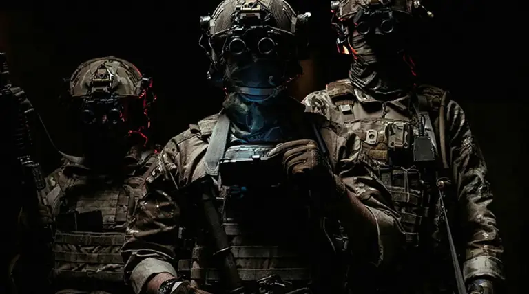 Three soldiers in combat gear wearing night vision goggles in a dark environment.