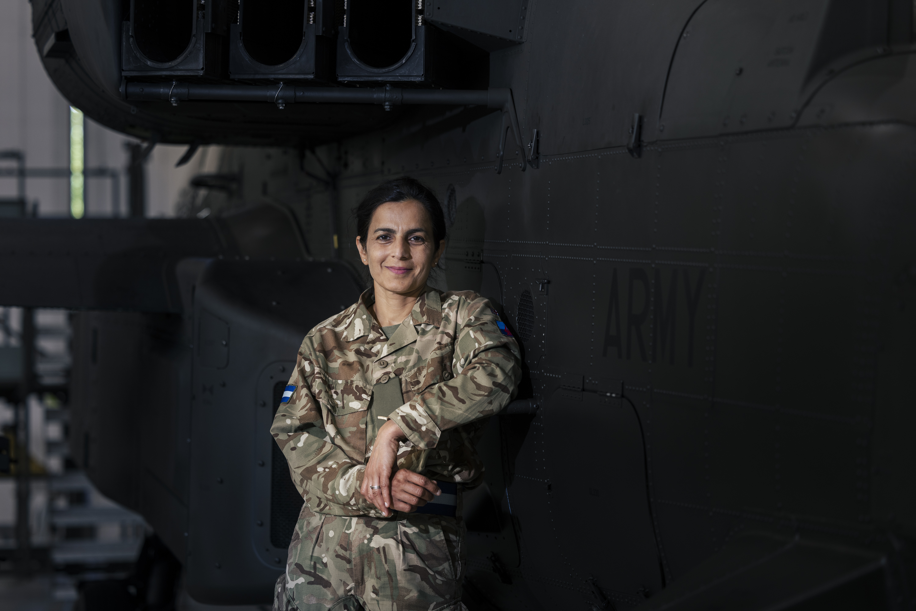 A person in military uniform stands in front of a helicopter with 