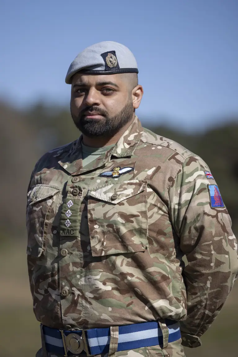 Soldiers in his camouflage unifrom with his arms behind his back and light blue berets on their heads stood outside.