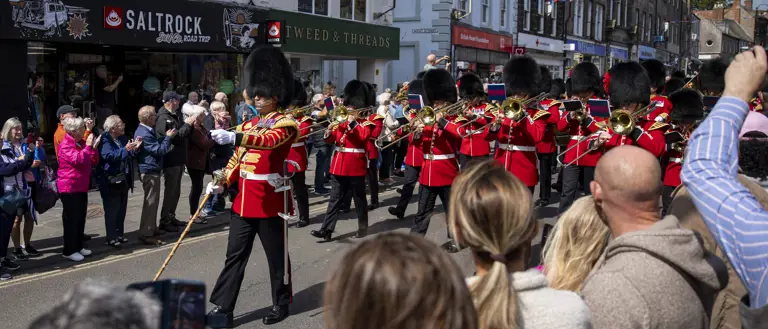 Soldiers in red tunics and black bearskin hats march through Berwick-upon-Tweed.