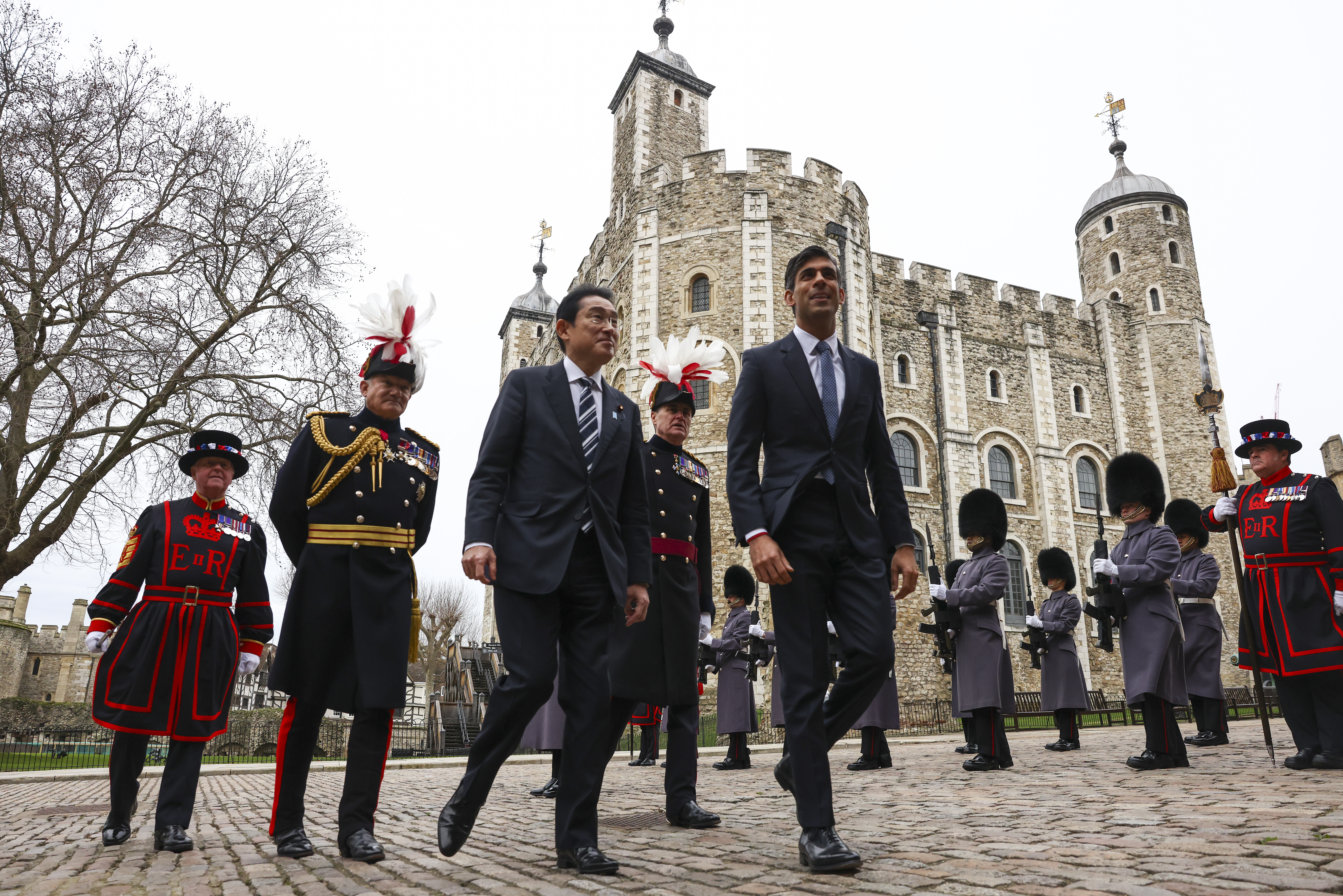 Prime Minister Rishi Sunak and Prime Minister Fumio Kishida walk past the Irish Guards' Guard of Honour. In attendance are also Tower of London Beefeaters and senior military personnel. The Tower of London is in the background.