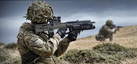 A soldier takes aim with their rifle. Attached underneath the barrel is a grenade launcher.