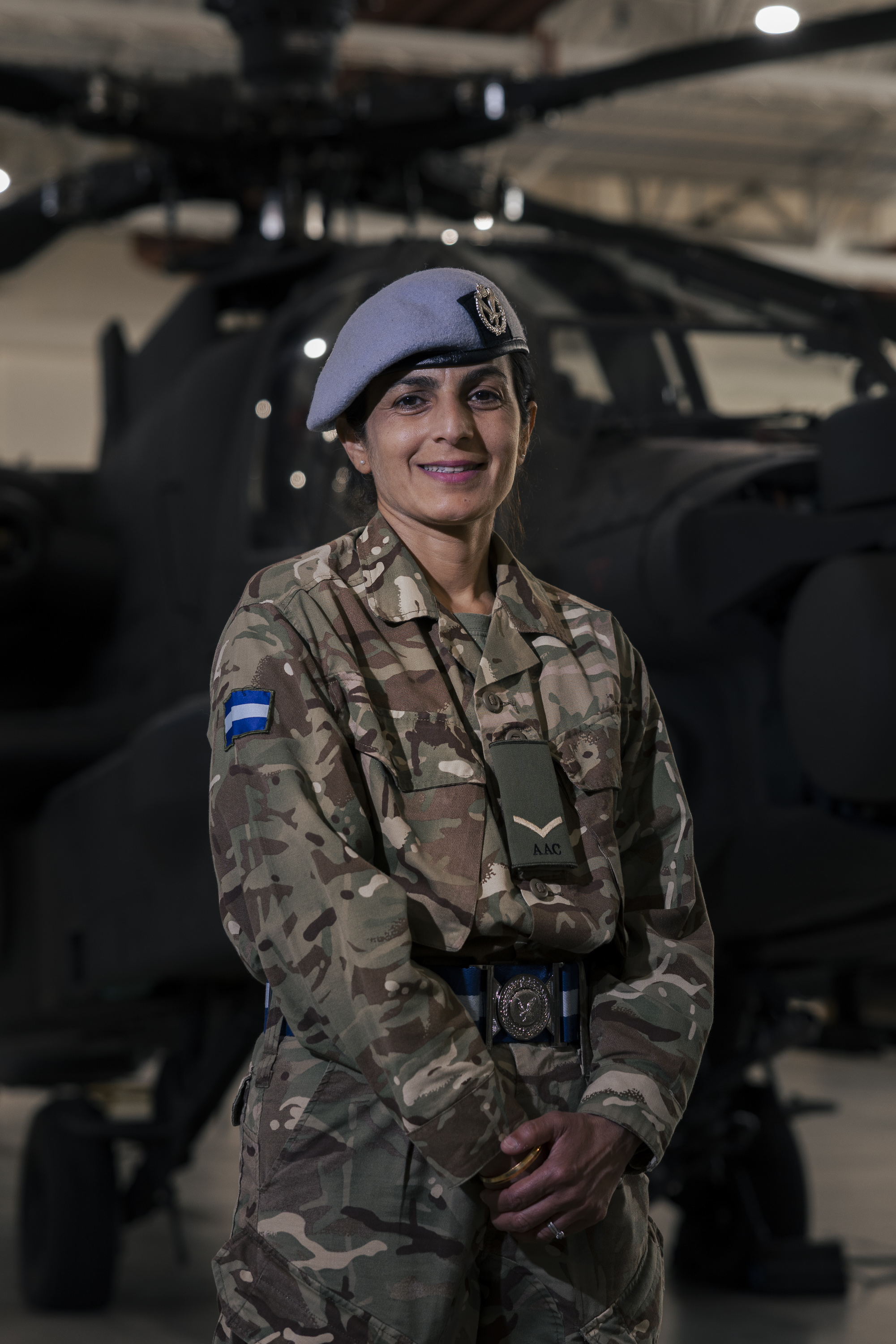A person wearing a military uniform standing in front of a helicopter.
