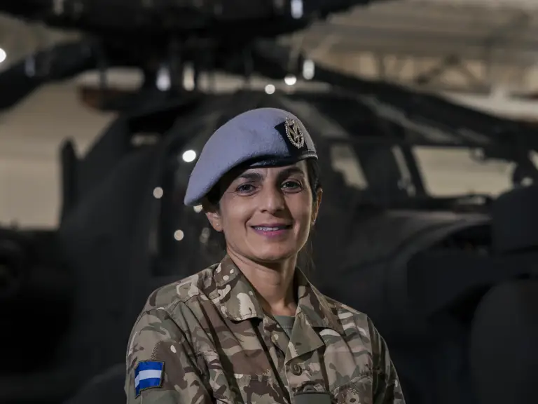 A person wearing a military uniform standing in front of a helicopter.