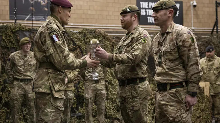 Two men in uniform are presented a trophy by a man in uniform.