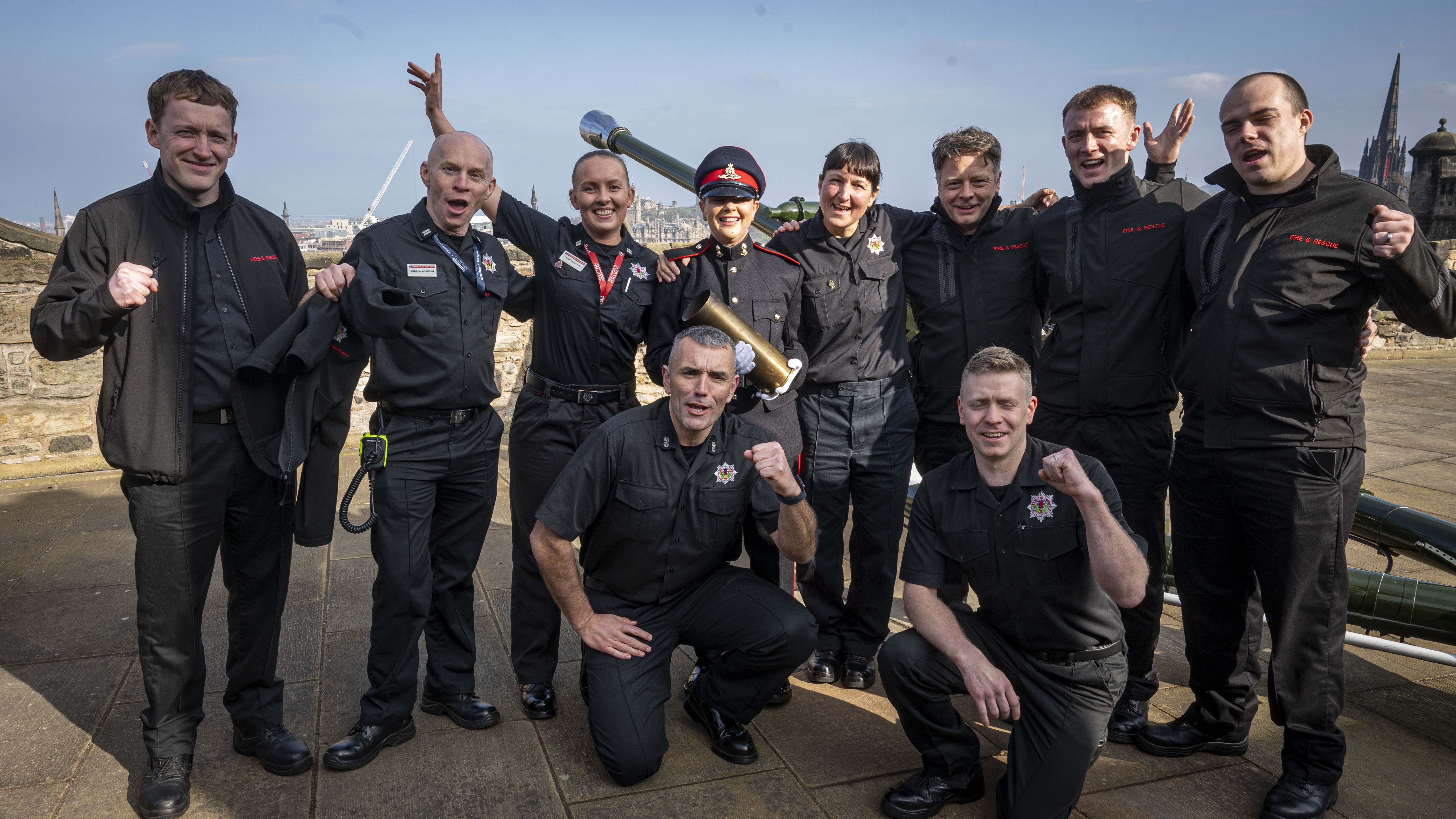 Gunner Caroline Gallagher is stood next to Watched by her fire crew and crew friends dressed in No.1 uniform dress holding an empty shell from the gun salute.  