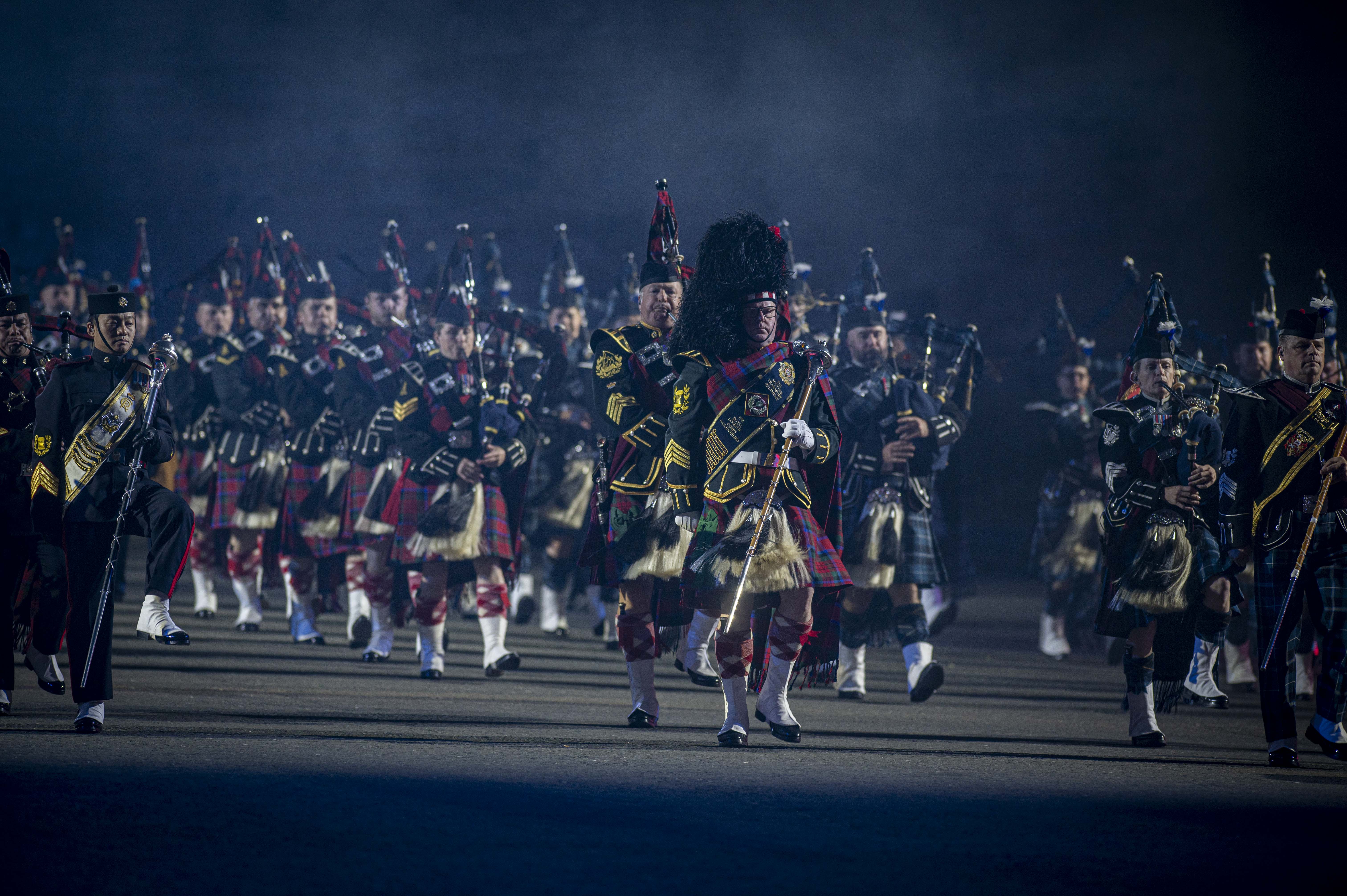 Pipes and Drummers dressed in ceremonnal uniforms, marching and playing doen the Esplanade at the Royal Edinburgh Military Tattoo.. 