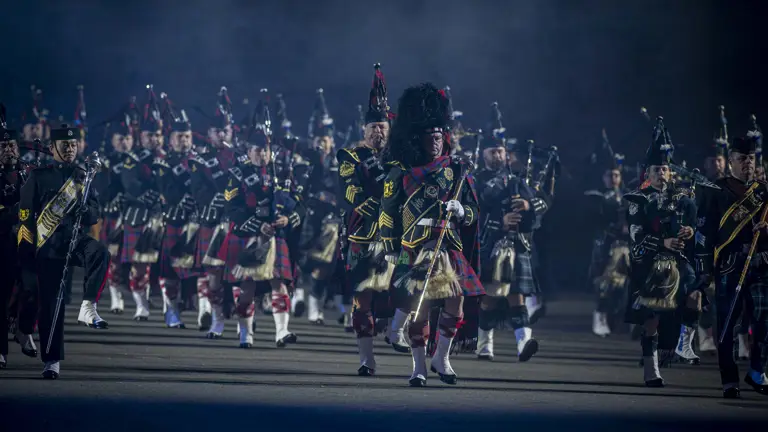 Pipes and Drummers dressed in ceremonnal uniforms, marching and playing doen the Esplanade at the Royal Edinburgh Military Tattoo..