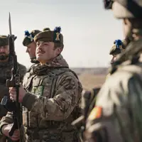 several soldiers from the Royal Regiment of Scotland are shown standing together on a training area, the main focus on a solider holding his rifle up looking at the bayonet