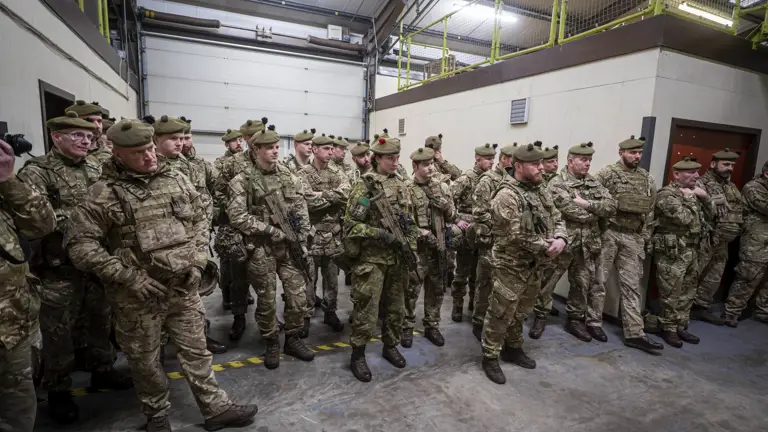 A large group of soldiers in uniform gather, some hold weapons.