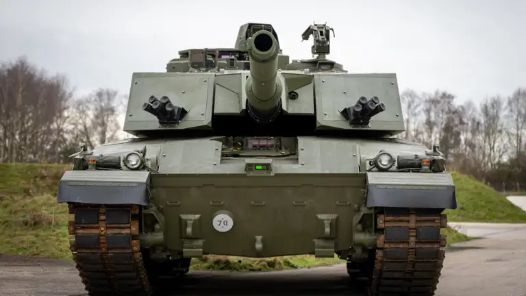 A military tank is positioned on a road, facing forward. It has a large central gun.