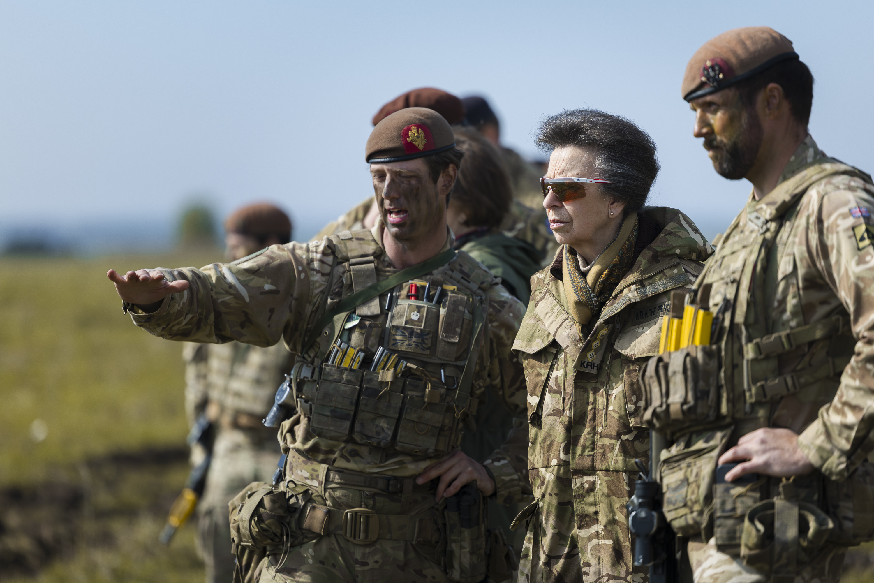 A group of individuals in military uniforms stand outdoors. 