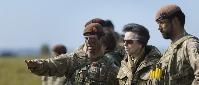 A group of individuals in military uniforms stand outdoors.