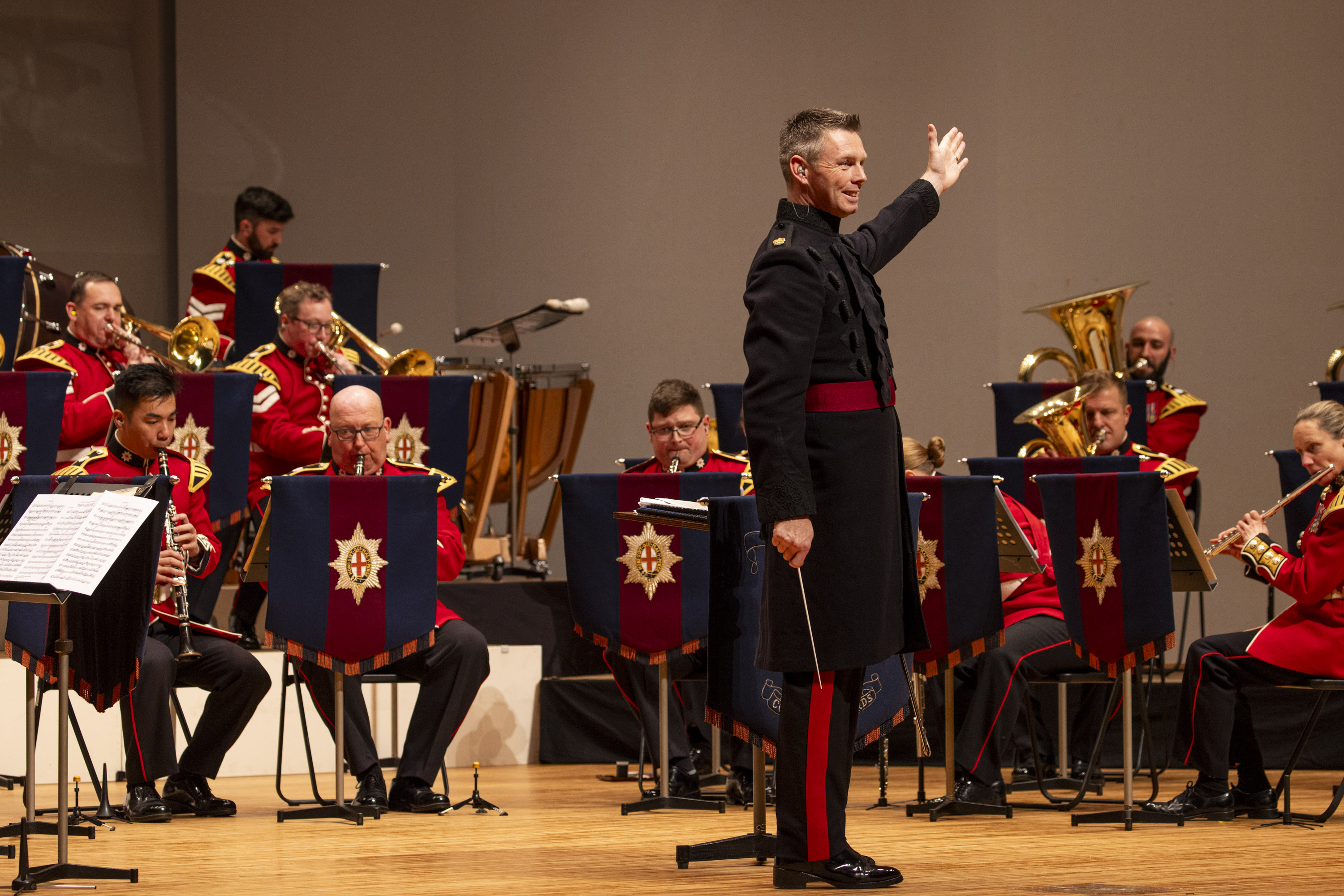 An Army band play on stage, the conductor is front and centre. 