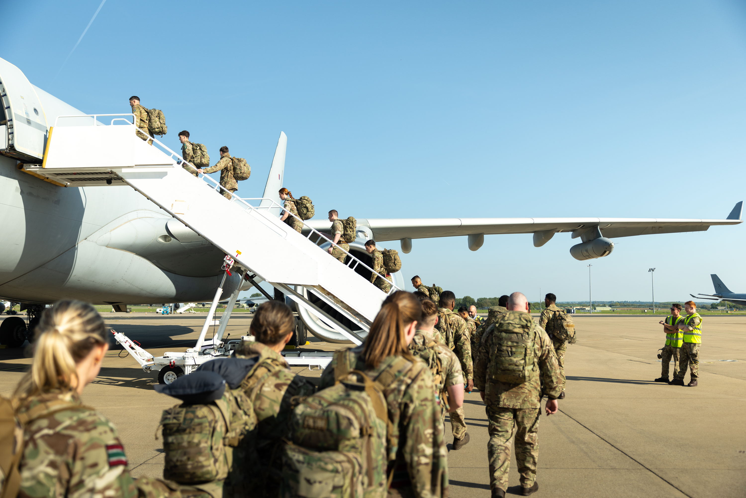 Soldiers wearing camouflage uniforms board a plane.