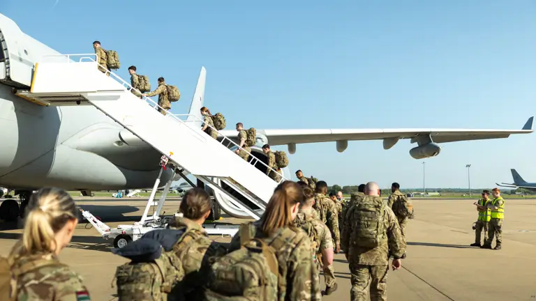 Soldiers wearing camouflage uniforms board a plane.