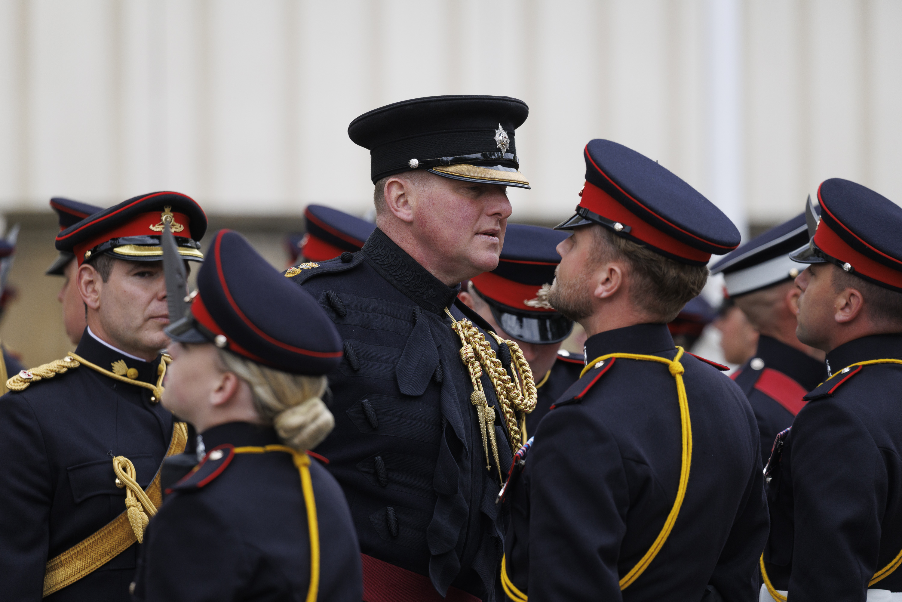 A group of uniformed individuals from the Royal Artillery stand in formation, wearing dark military attire.