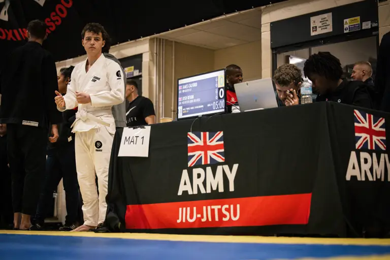 A person in a martial arts gi stands near a table marked