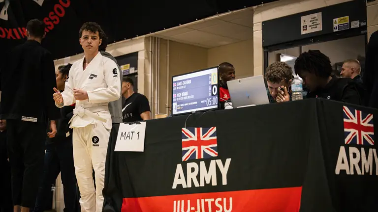 A person in a martial arts gi stands near a table marked