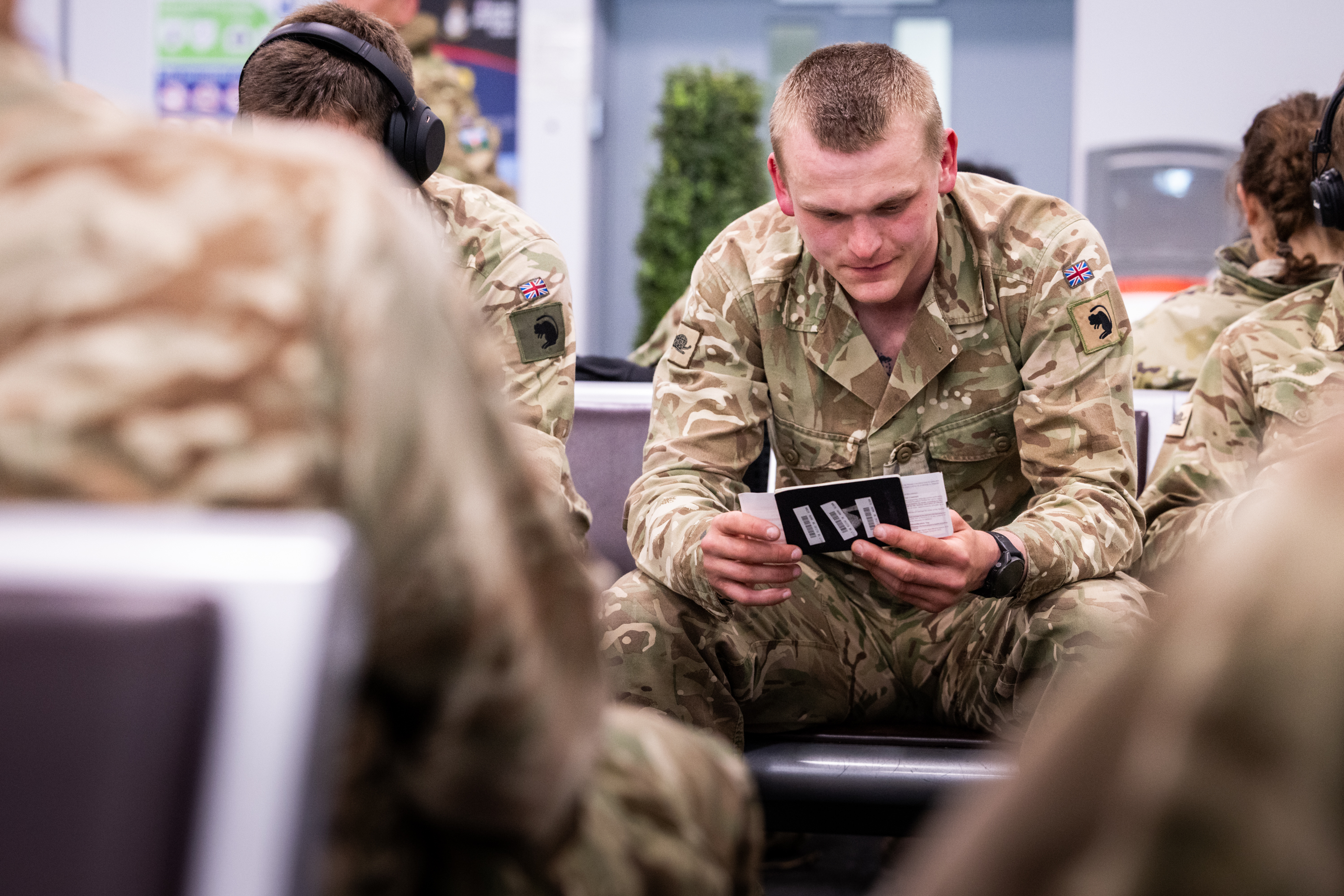A soldier wearing a camouflage uniform checks his boarding pass before a flight.
