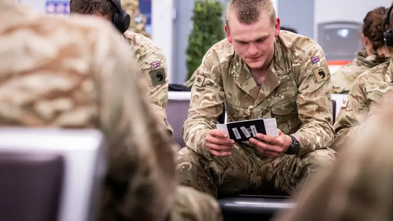 A soldier wearing a camouflage uniform checks his boarding pass before a flight.