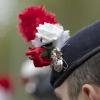 A soldier's beret with a red and white hackle, a red rose and a white rose.
