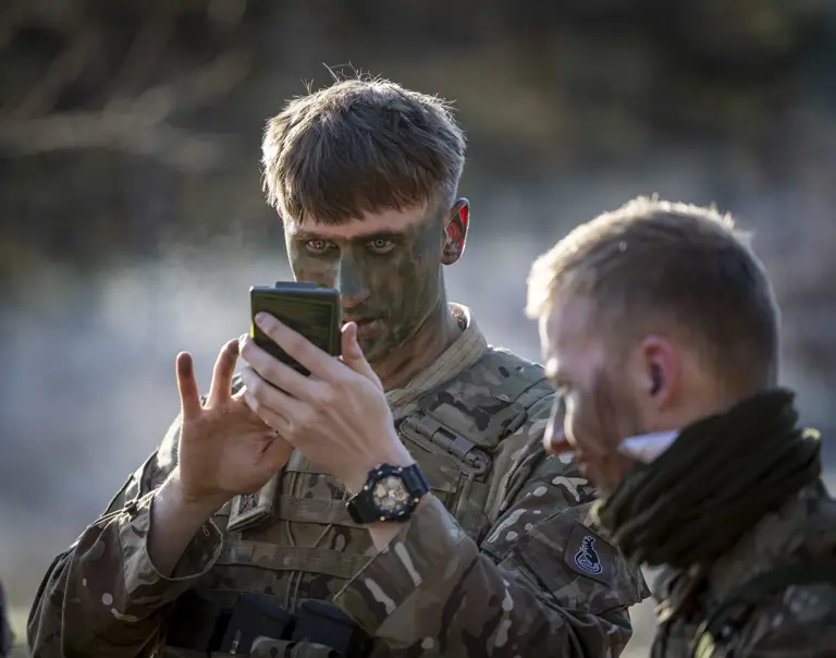 A man in uniform applies camouflage. 