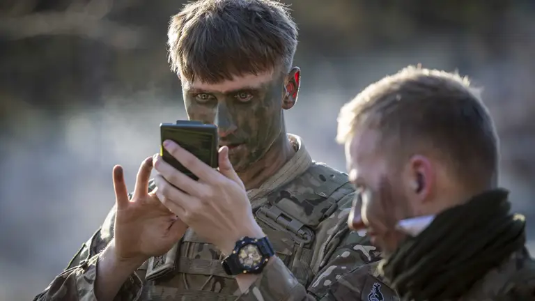 A man in uniform applies camouflage.
