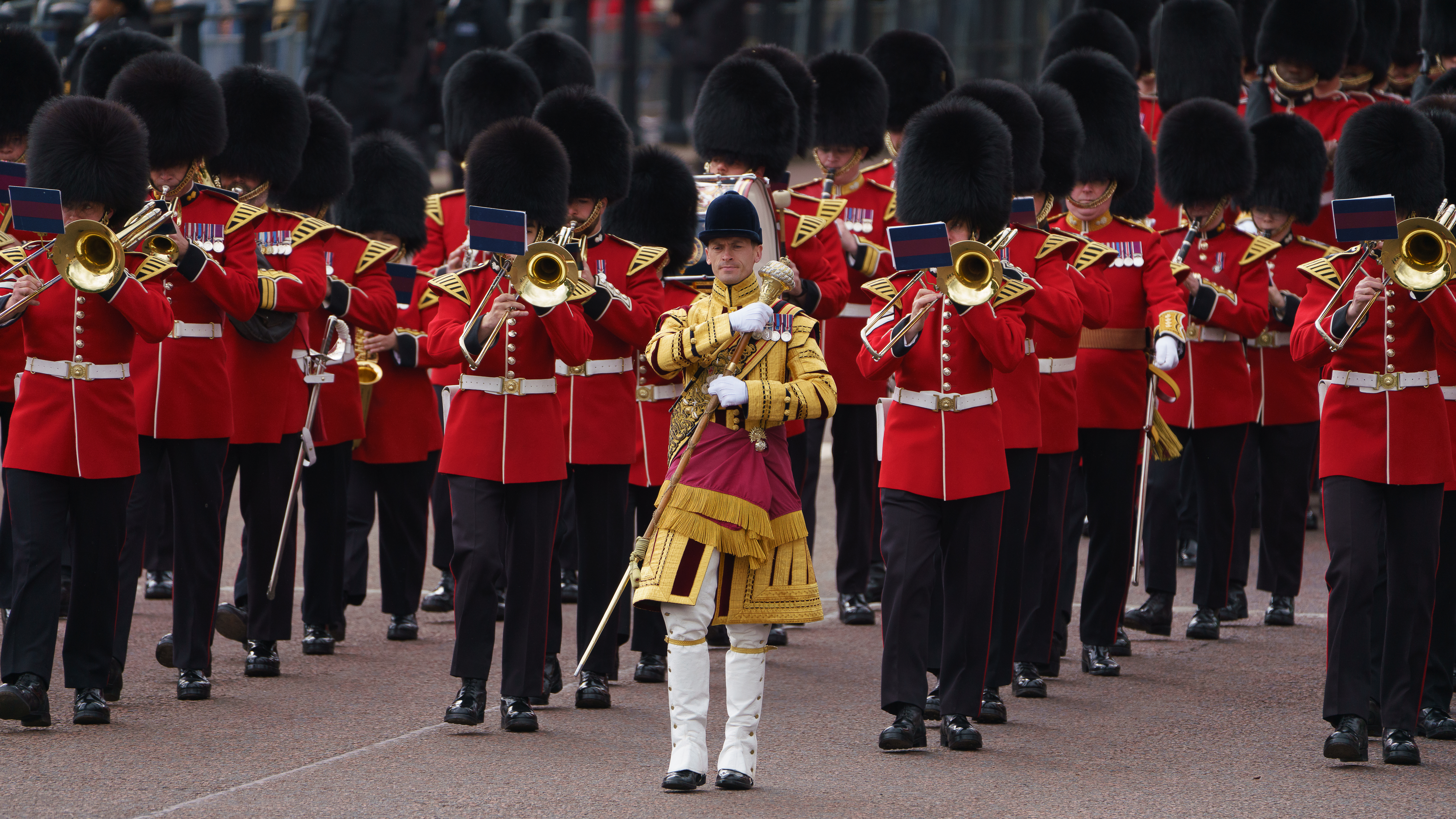 A marching band in red uniforms is performing, with members playing brass instruments. 