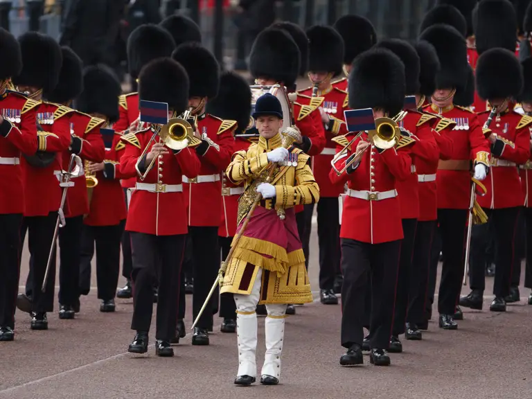A marching band in red uniforms is performing, with members playing brass instruments.