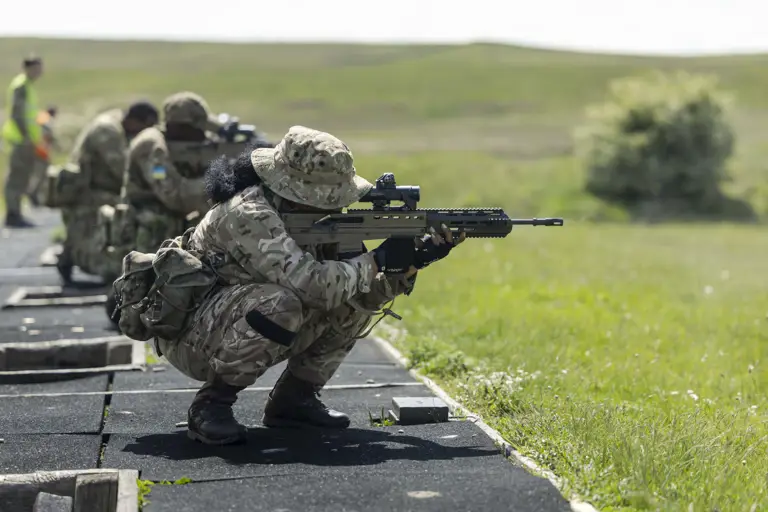 Military personnel in camouflage uniforms are training with rifles outdoors.