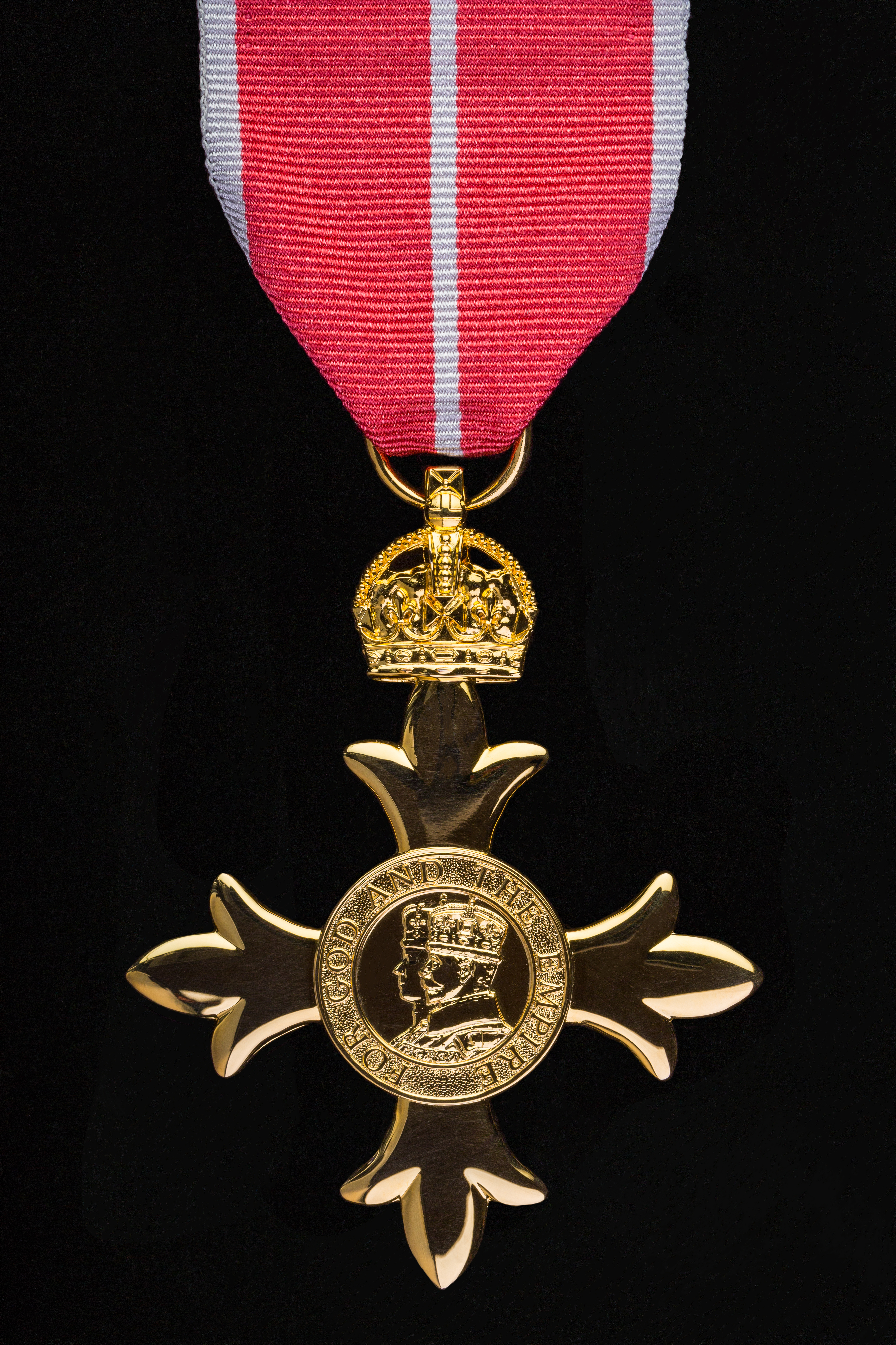 Gold medal in the shape of a cross with a crowned profile of a monarch in the centre. 