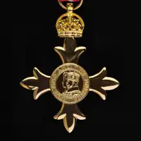 Gold medal in the shape of a cross with a crowned profile of a monarch in the centre.