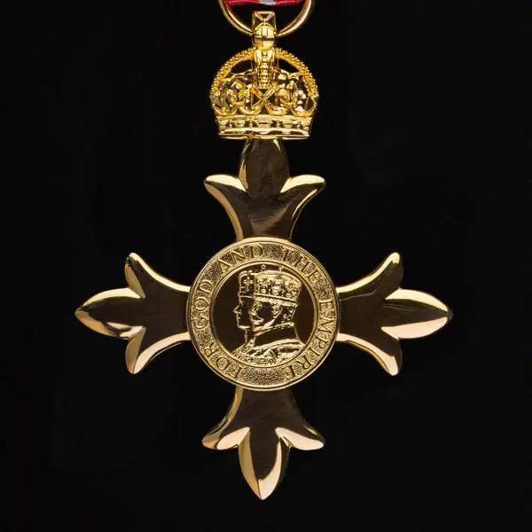 Gold medal in the shape of a cross with a crowned profile of a monarch in the centre.