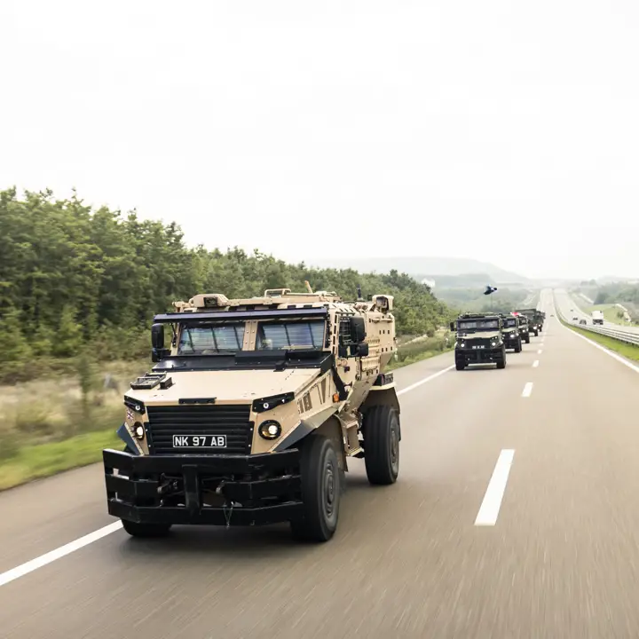 Foxhound vehicles driving down a road in convoy