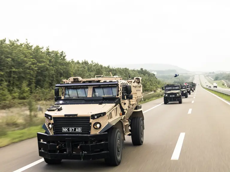 Foxhound vehicles driving down a road in convoy