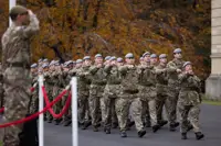 Military personnel in grey berets march in unison.