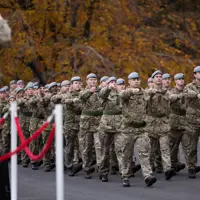 Military personnel in grey berets march in unison.