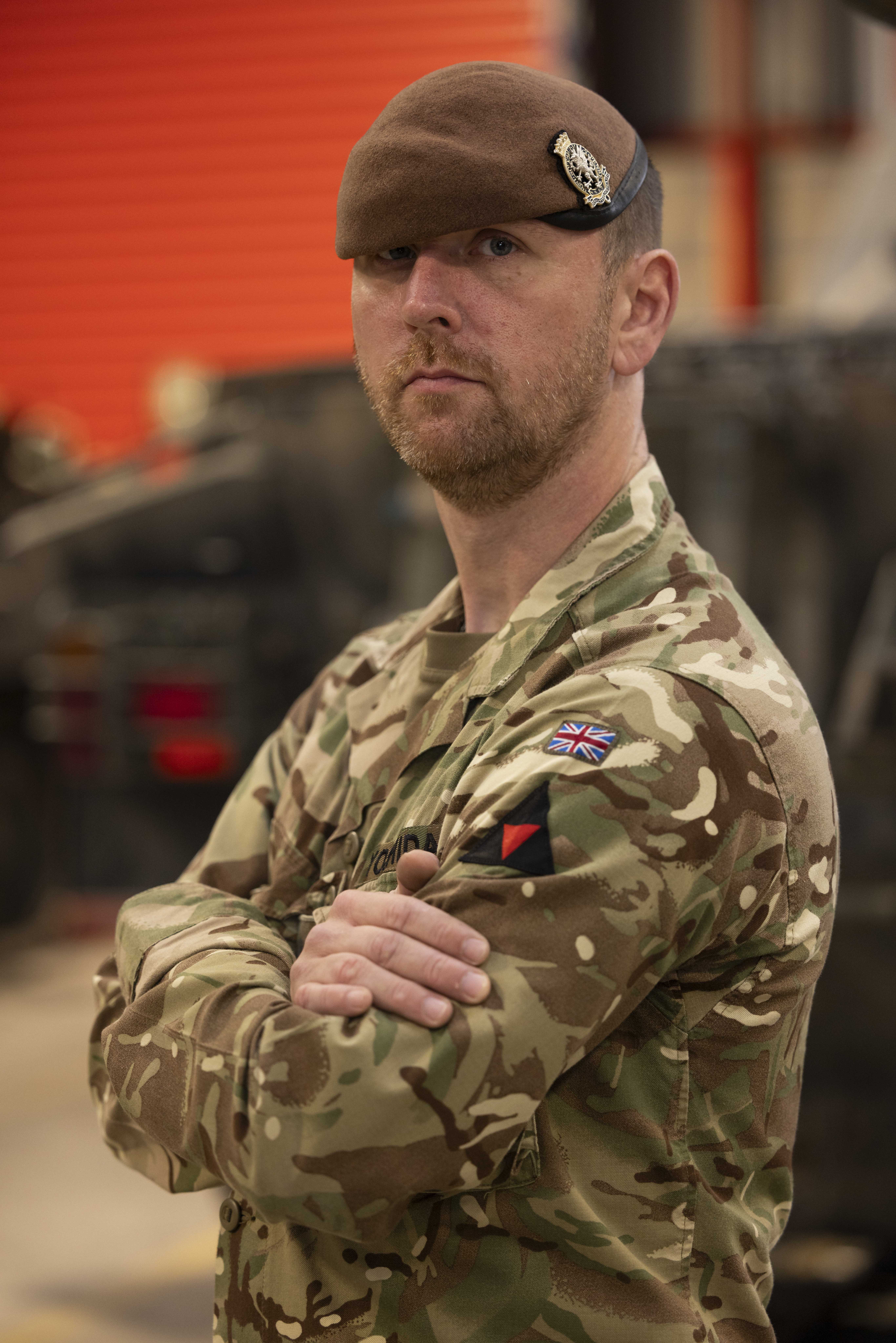 A man in uniform stands with his arms crossed. 
