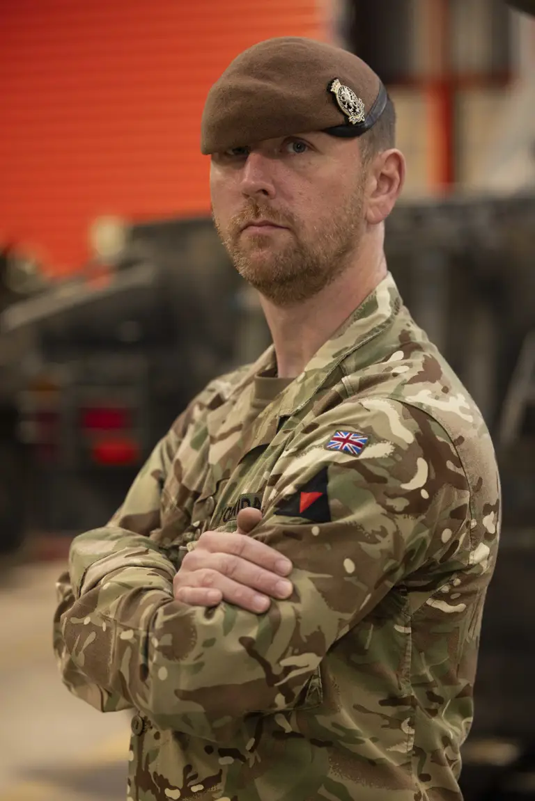 A man in uniform stands with his arms crossed.