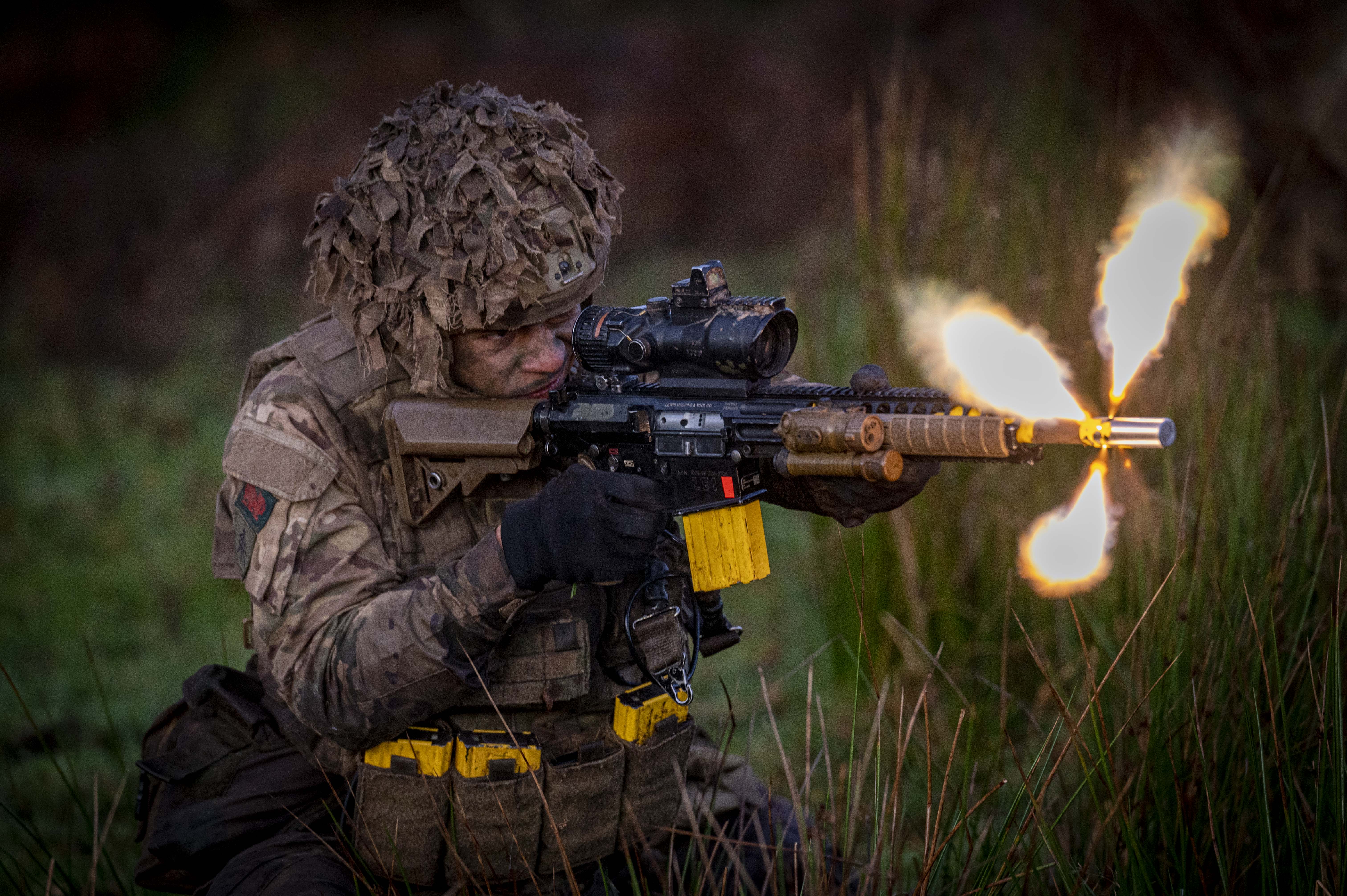 A soldier wearing camouflage uniform fires a rifle.