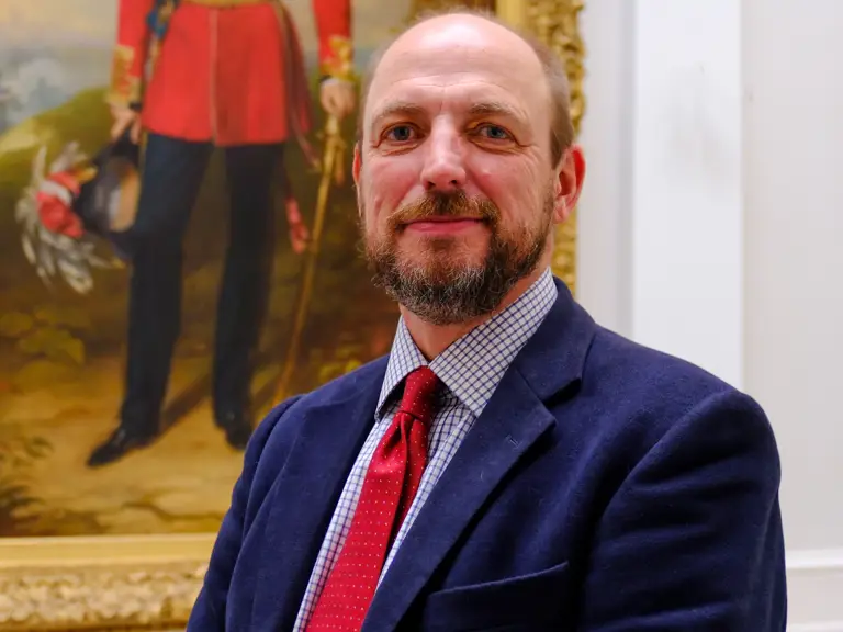 Academic in suit stood in front of painting