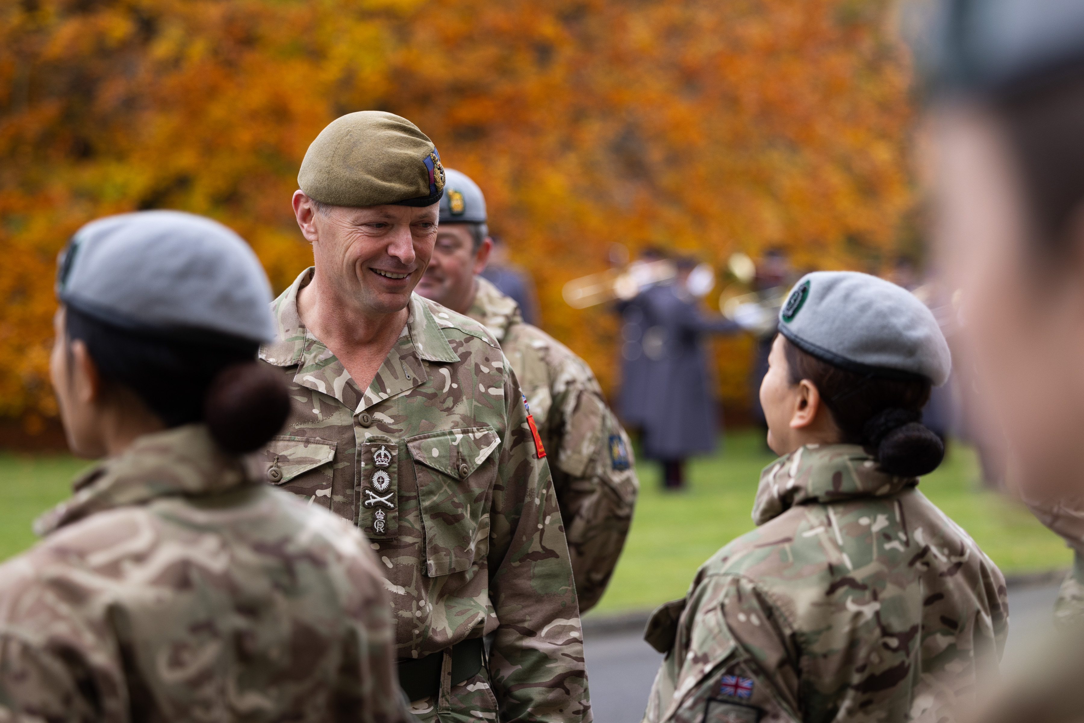 A senior Army Officer smiles at a lady in uniform. 