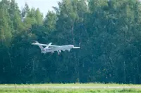 An unmanned aerial vehicle is pictured flying beneath a tree line.
